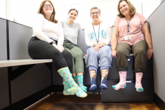 four women smiling, showing their wild socks